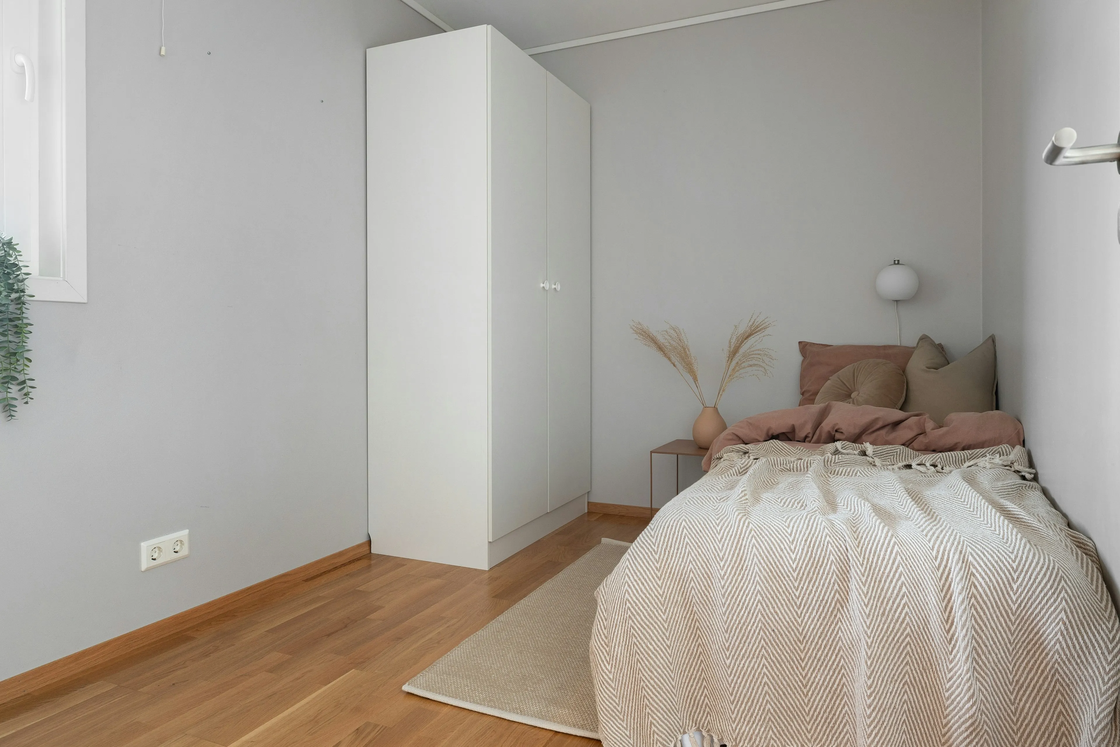 Single bed with a cream throw and dried pampas grass (reference image)