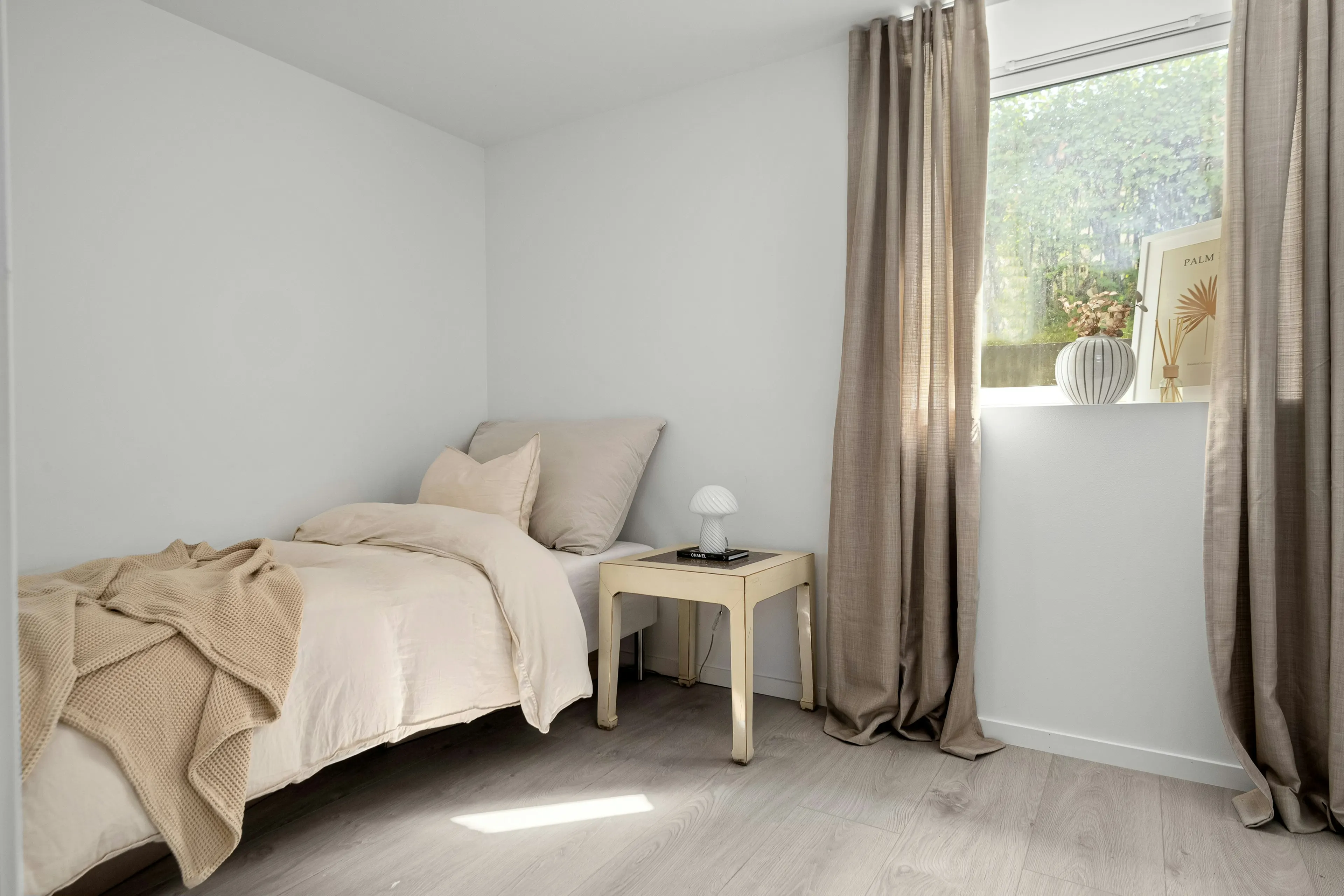 Single bed with cream bedding and linen curtains (reference image)